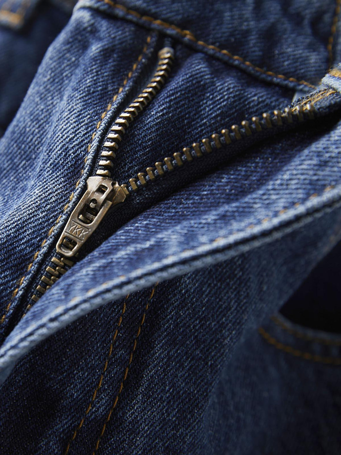 Intricate look at TALISHKO's denim zipper and stitching on barrel leg jeans.