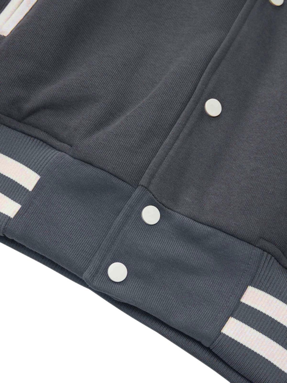 A close-up of the TALISHKO bomber jacket's button and hem details, showcasing striped accents.