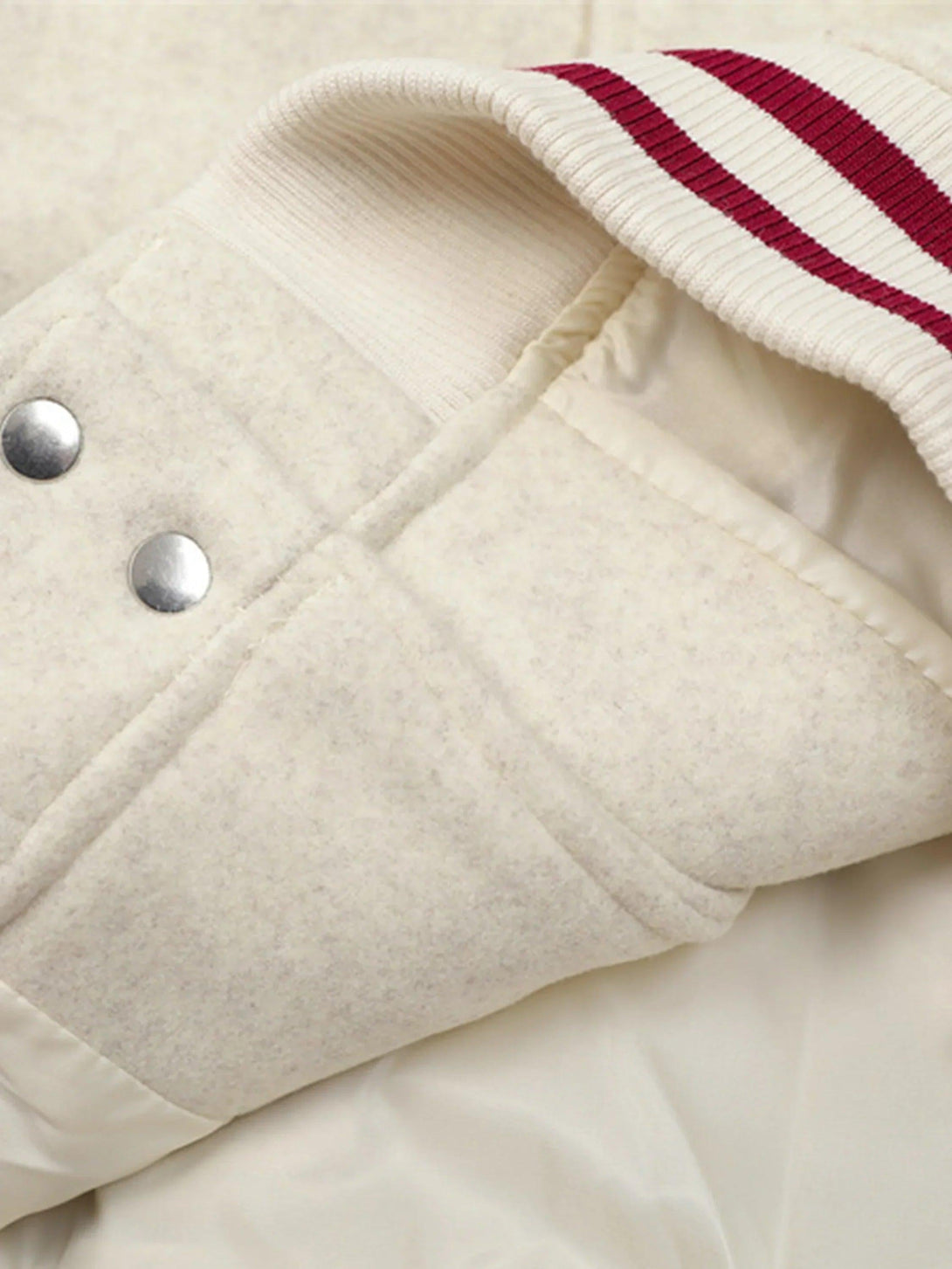 A tight crop highlights the TALISHKO varsity jacket's texture and striped cuff detail.