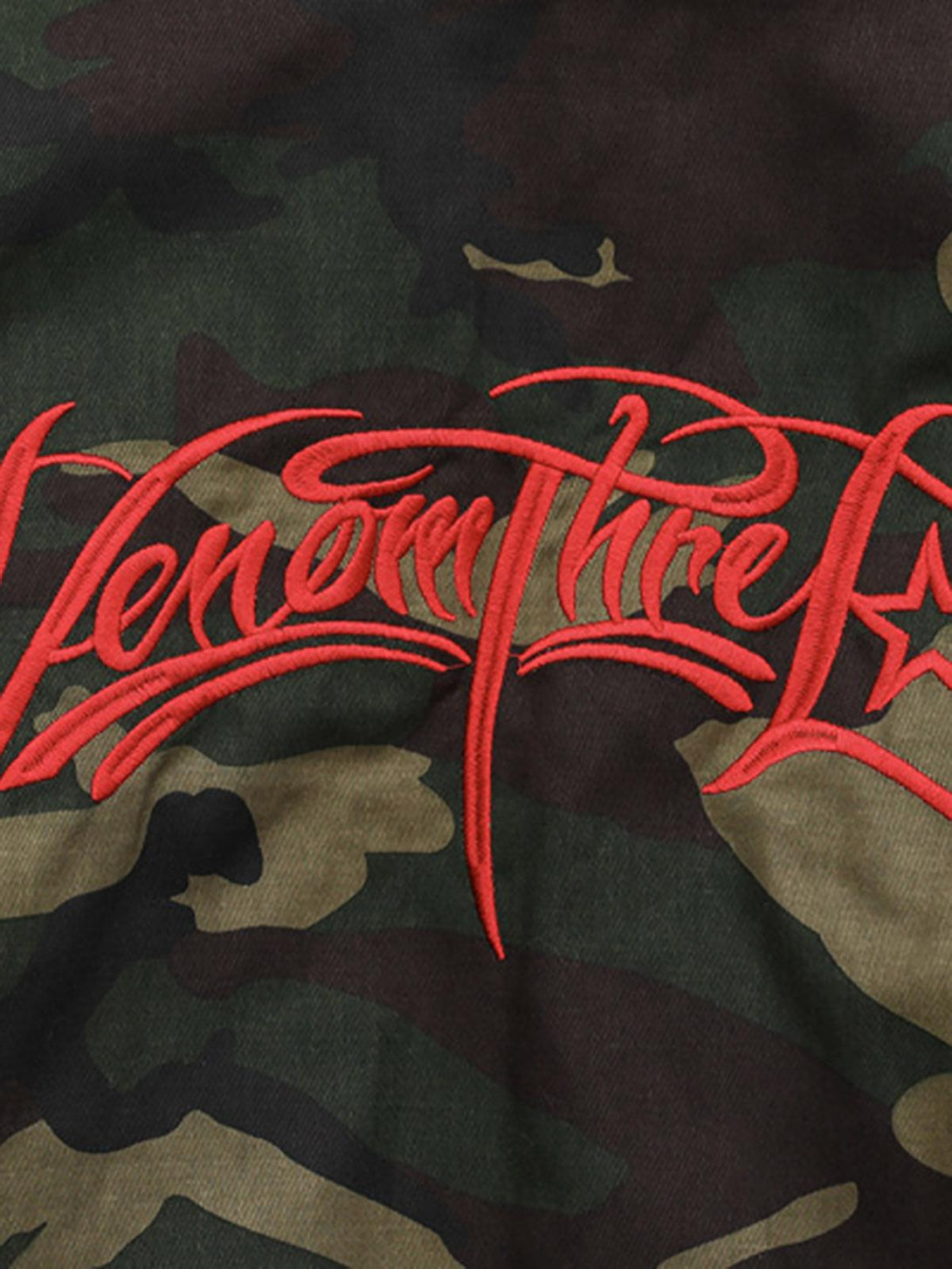 Intricate look at red embroidery detail on camo jacket fabric, highlighting TALISHKO's style.