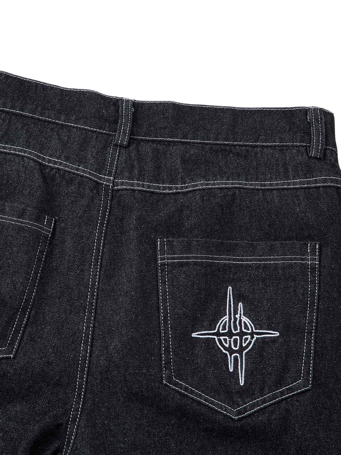 Intricate look at TALISHKO's embroidered flame design on the back pocket of baggy jeans.