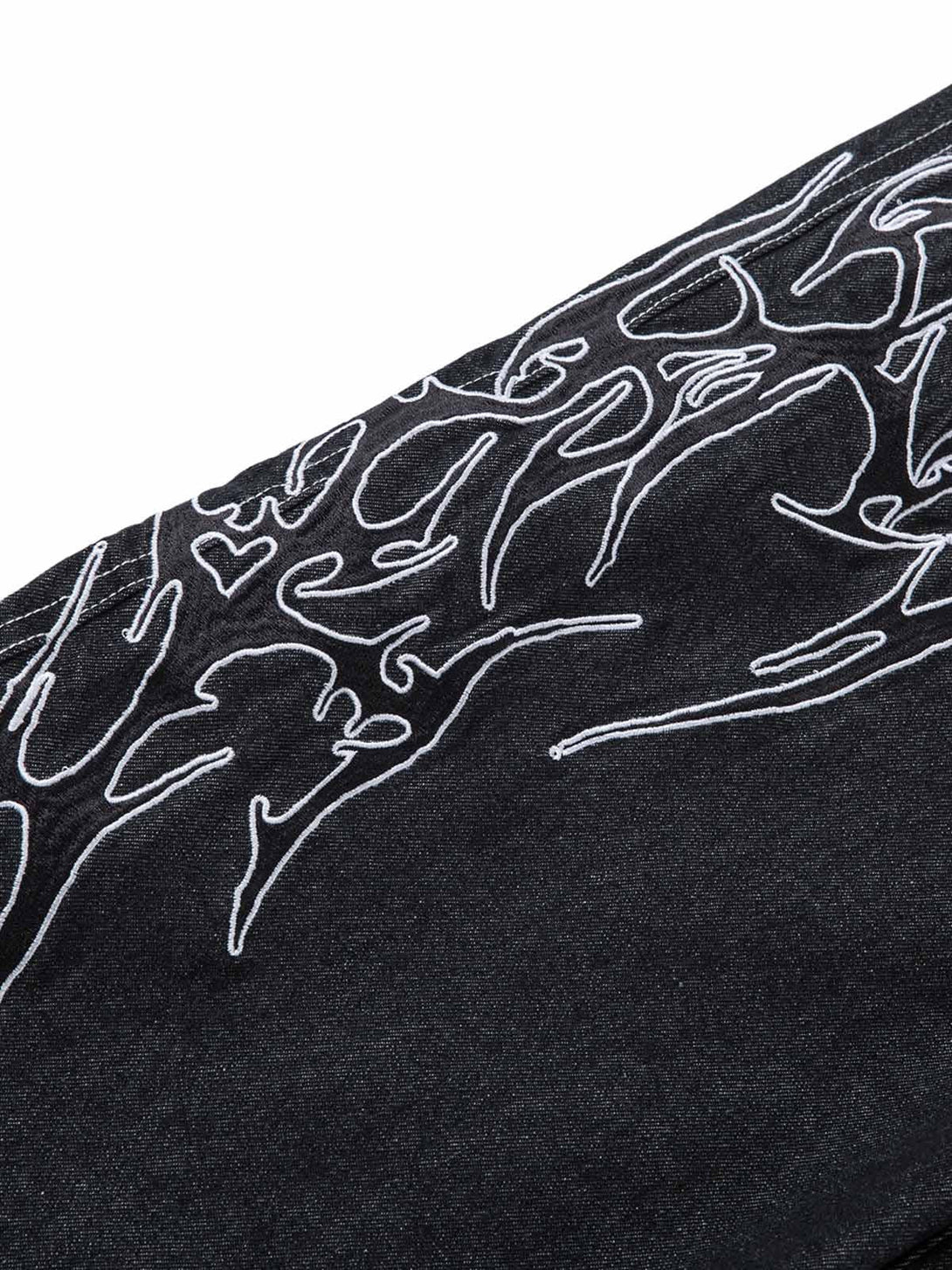 Intricate embroidery detail on TALISHKO's flame baggy jeans, accentuating unique texture.