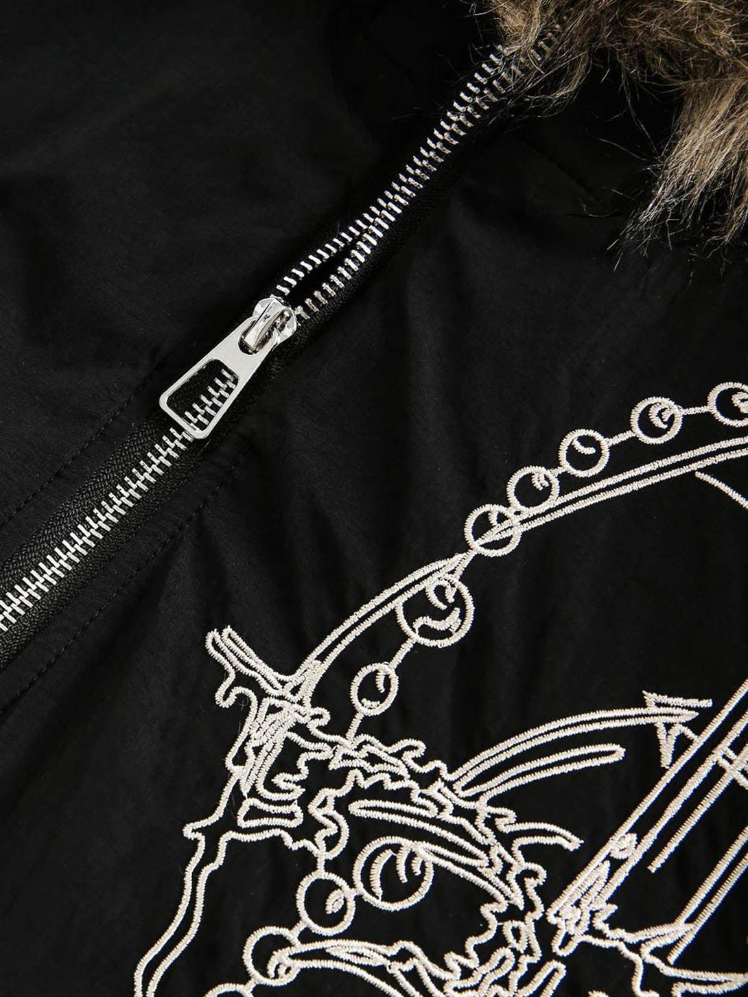 A close-up of the TALISHKO quilted jacket, highlighting intricate embroidery and zipper detail.