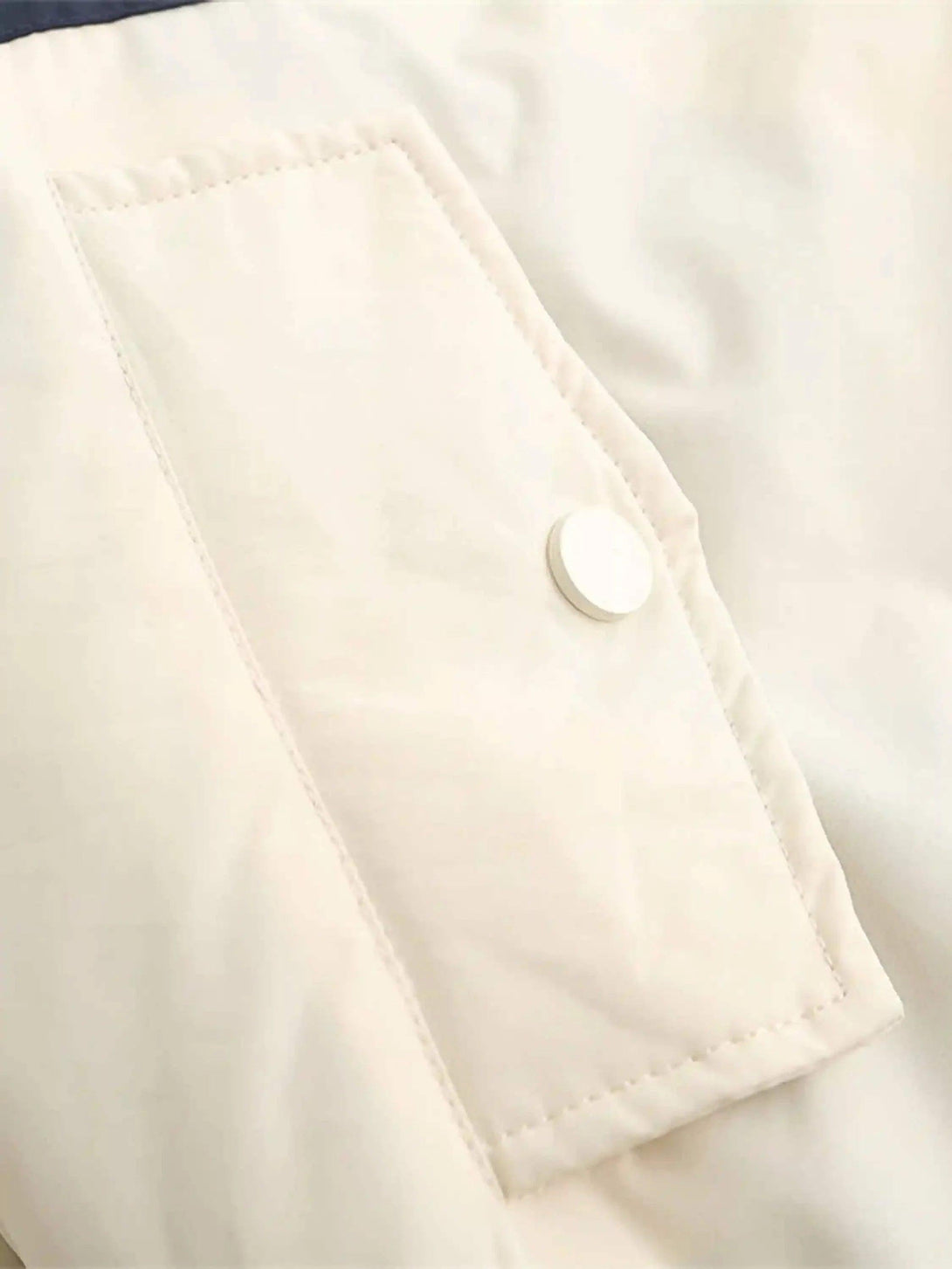 A detailed view of TALISHKO's cotton jacket pocket with sleek stitching and a button closure.