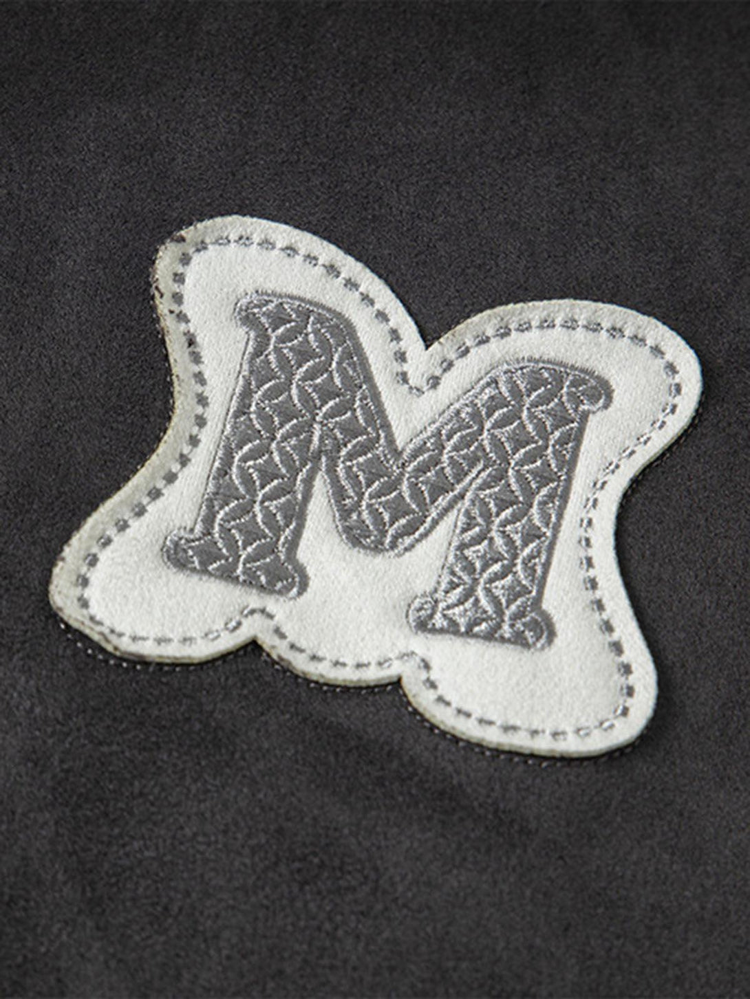 Intricate look at the embroidered "M" detail on the TALISHKO oversized T-shirt.