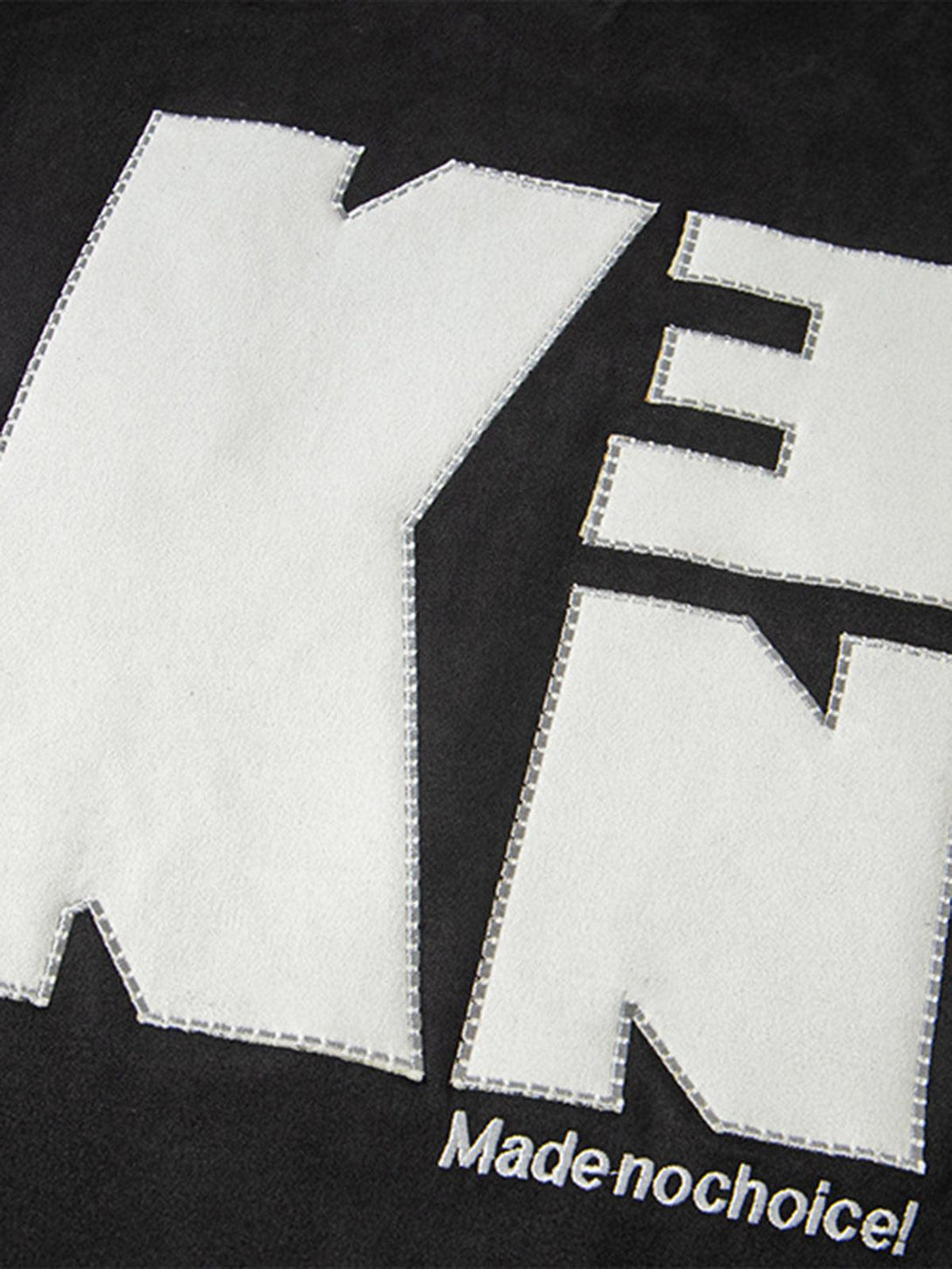 A close-up of TALISHKO's oversized T-shirt, highlighting bold embroidered lettering detail.