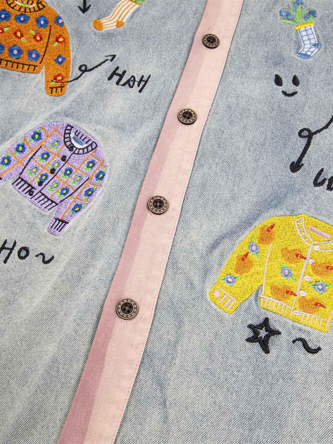 Intricate look at the embroidered patches on TALISHKO's denim shirt, highlighting unique designs.