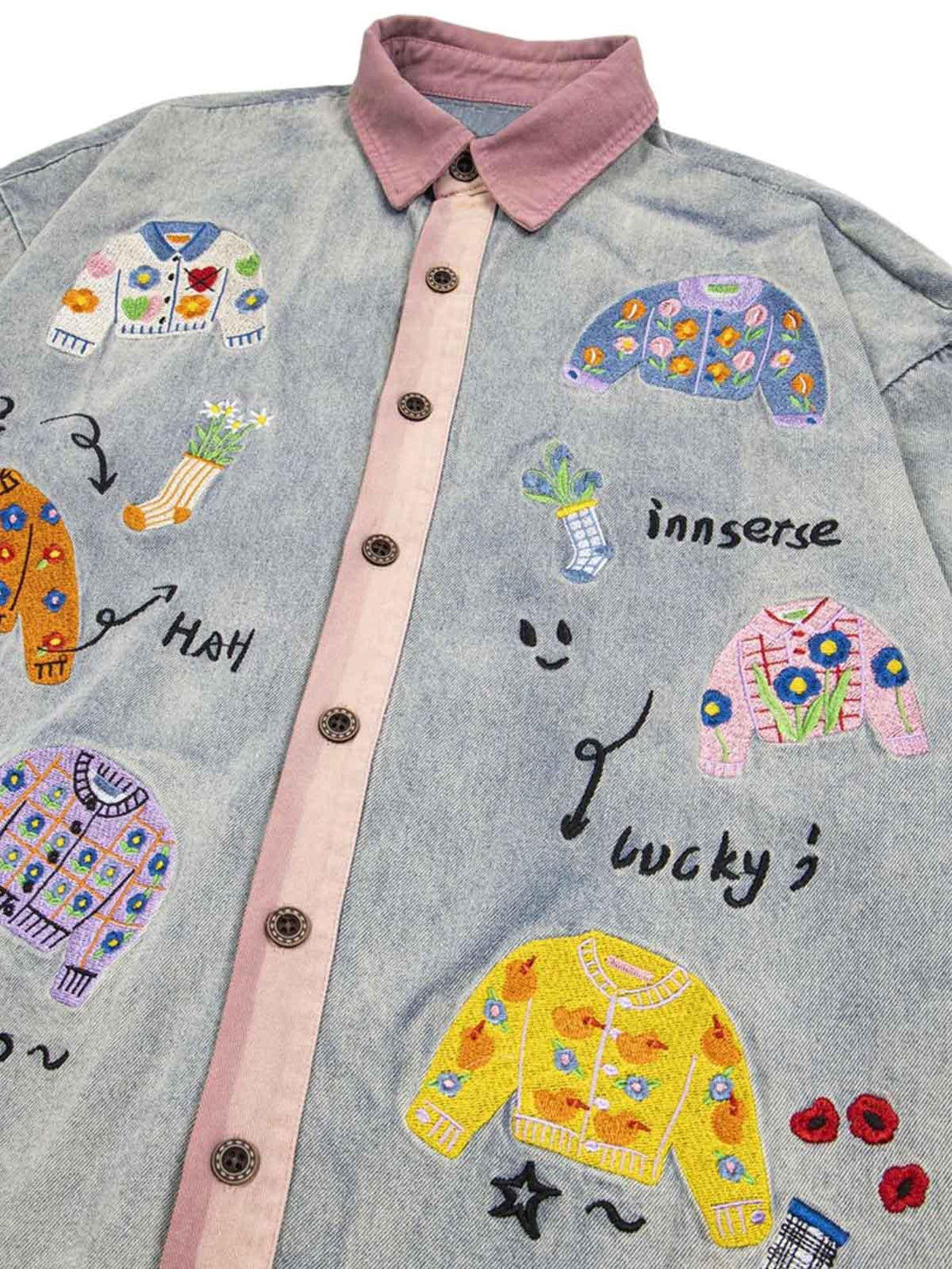 A detailed view of TALISHKO's denim shirt, featuring colorful embroidered patches and playful motifs.