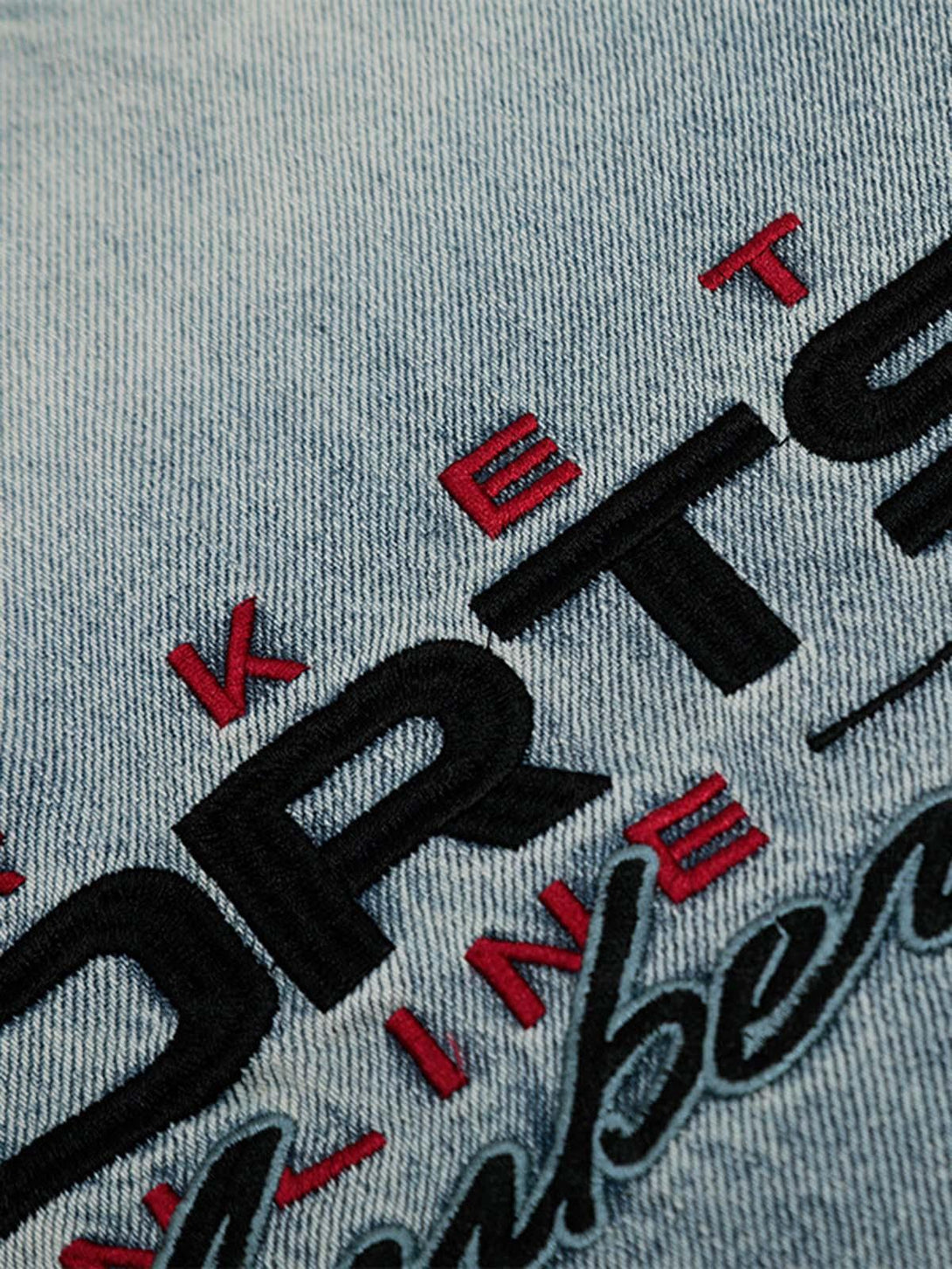 Intricate embroidery detail on washed denim by TALISHKO, highlighting unique texture and style.