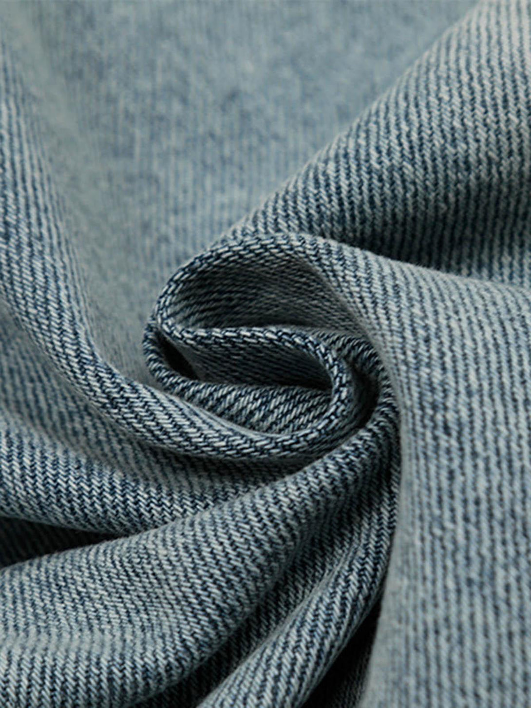 Zoomed-in texture of washed and distressed denim by TALISHKO, highlighting intricate weave.