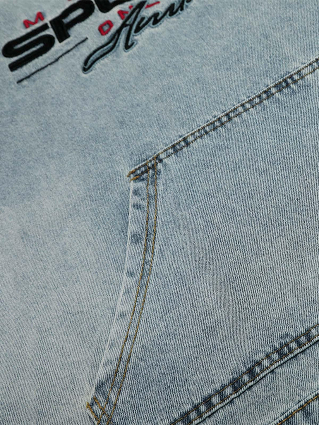 A detailed view of the embroidered design on a washed denim hoodie by TALISHKO, highlighting texture.