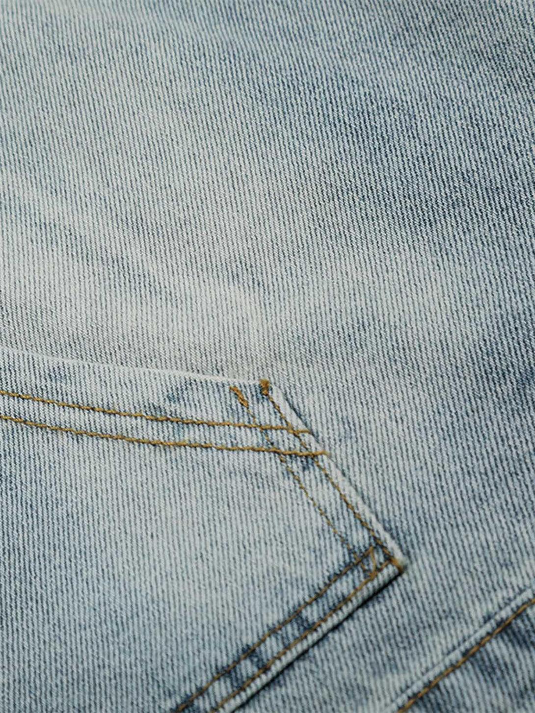 Focusing on the washed denim fabric and stitching by TALISHKO, showcasing intricate texture.