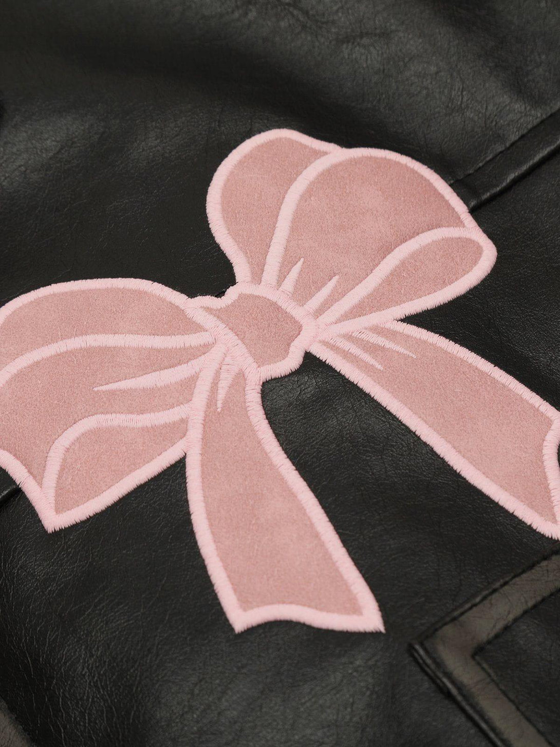 A close-up of the TALISHKO jacket, highlighting pink bow embroidery on black faux leather.