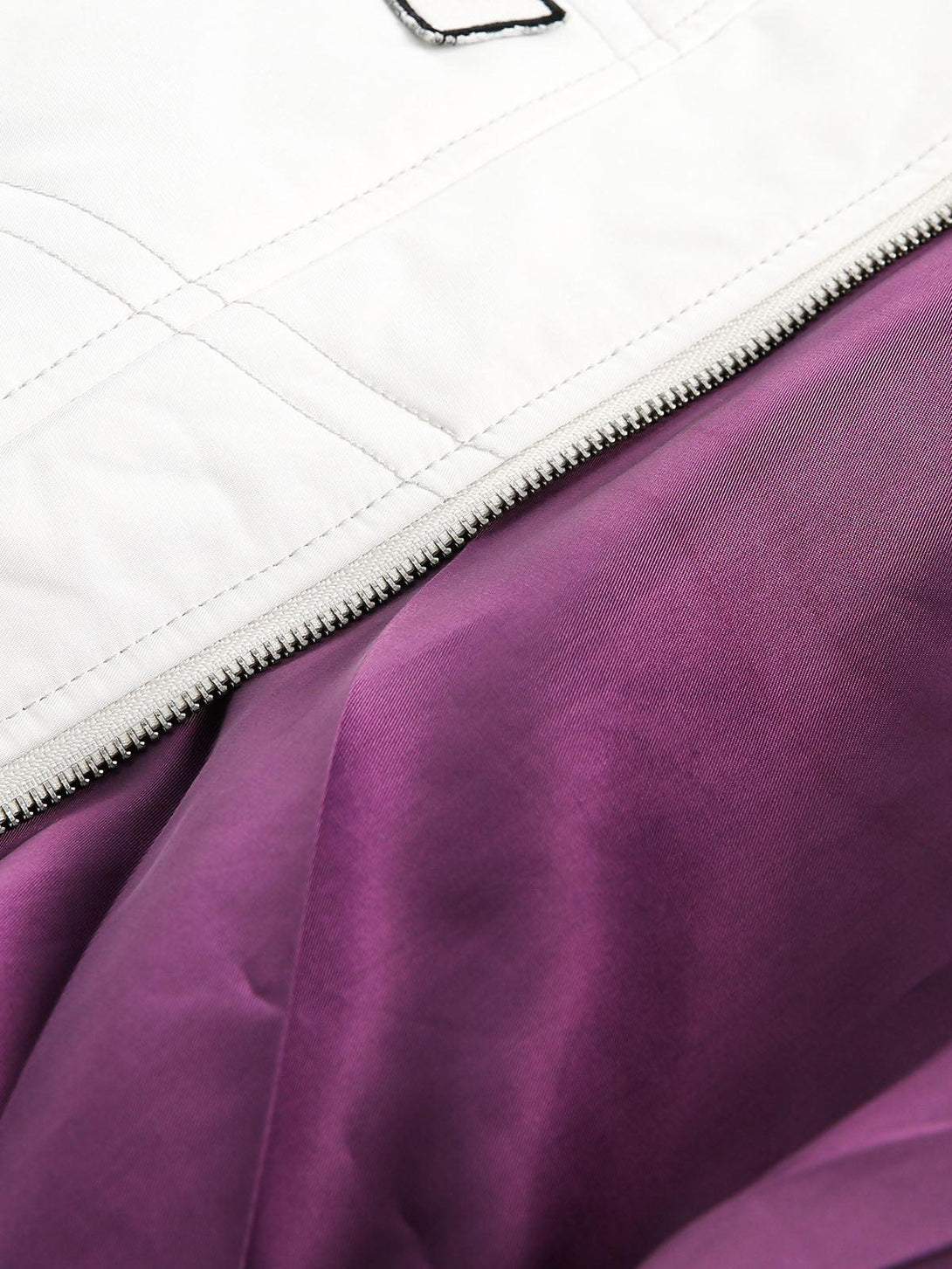 Zoomed-in texture of the TALISHKO bomber jacket's lining, highlighting the vibrant purple fabric.