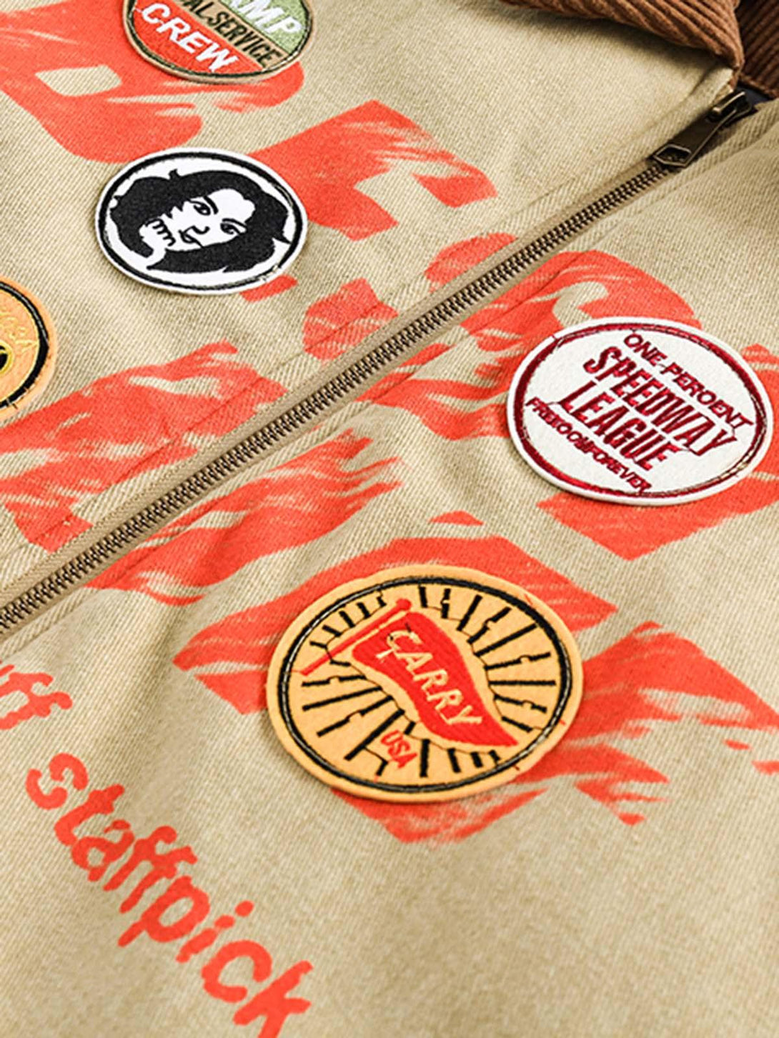 A tight crop highlighting embroidery patches on a TALISHKO barn jacket with vibrant red accents.