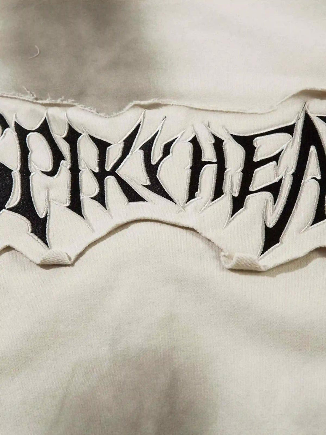 A detailed look at TALISHKO's embroidered design on a zip-up hoodie, showcasing edgy style.