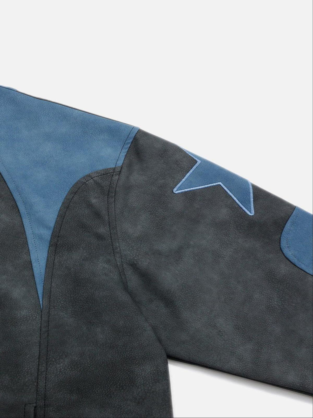 A close-up of TALISHKO's cropped racing jacket, showcasing blue star embroidery on gray fabric.