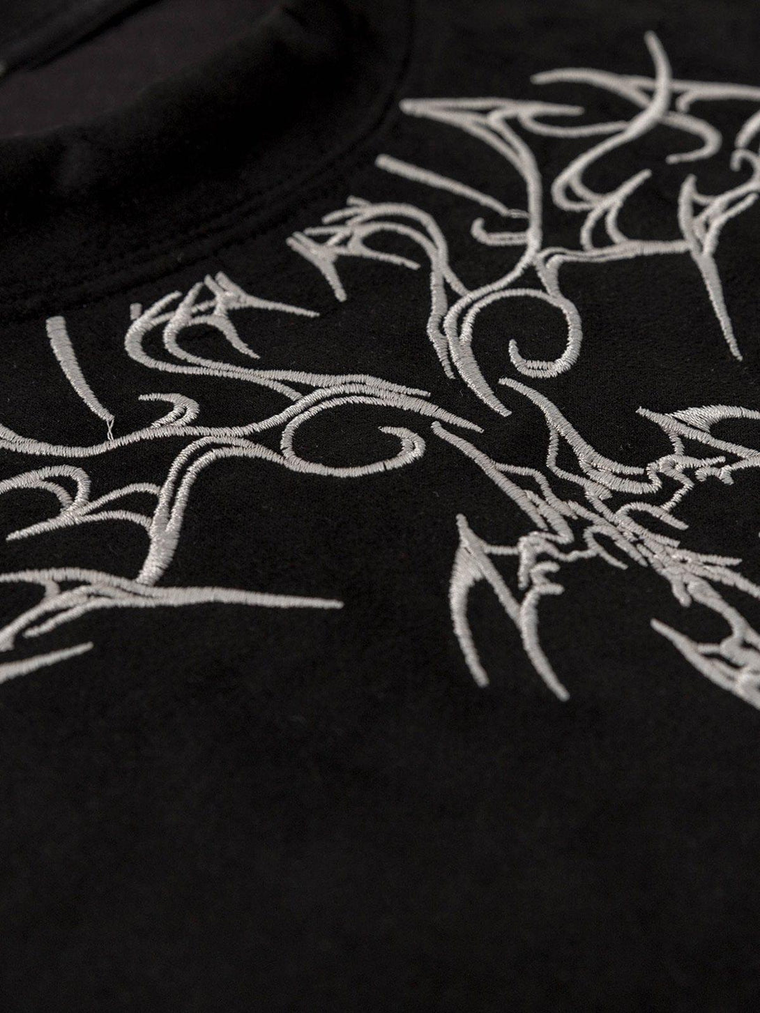 Intricate look at the embroidery on a black suede tee by TALISHKO, perfect for stylish summer days.