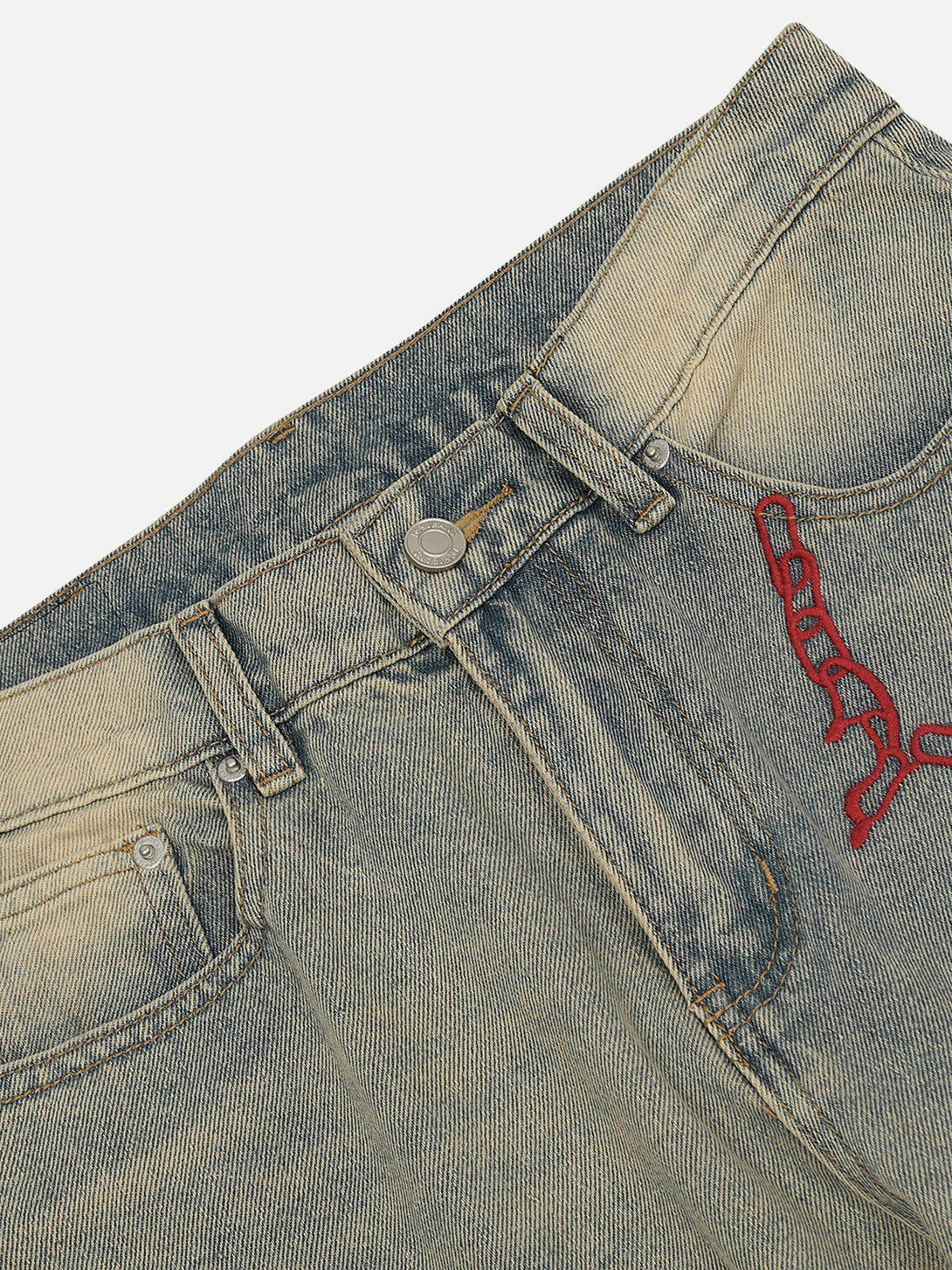 Zoomed-in texture of TALISHKO jeans with red embroidery, highlighting unique design details.