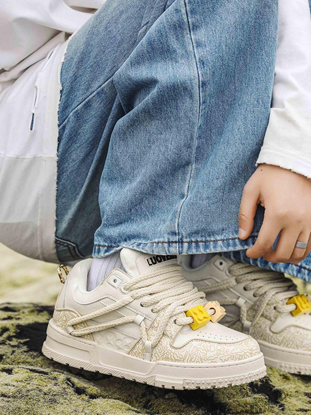 TALISHKO sneakers in cream, featuring intricate patterns and thick laces, styled with denim.