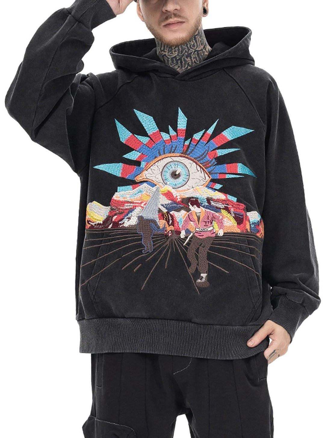 Model wearing a black TALISHKO hoodie with bold evil eye embroidery and colorful design elements.
