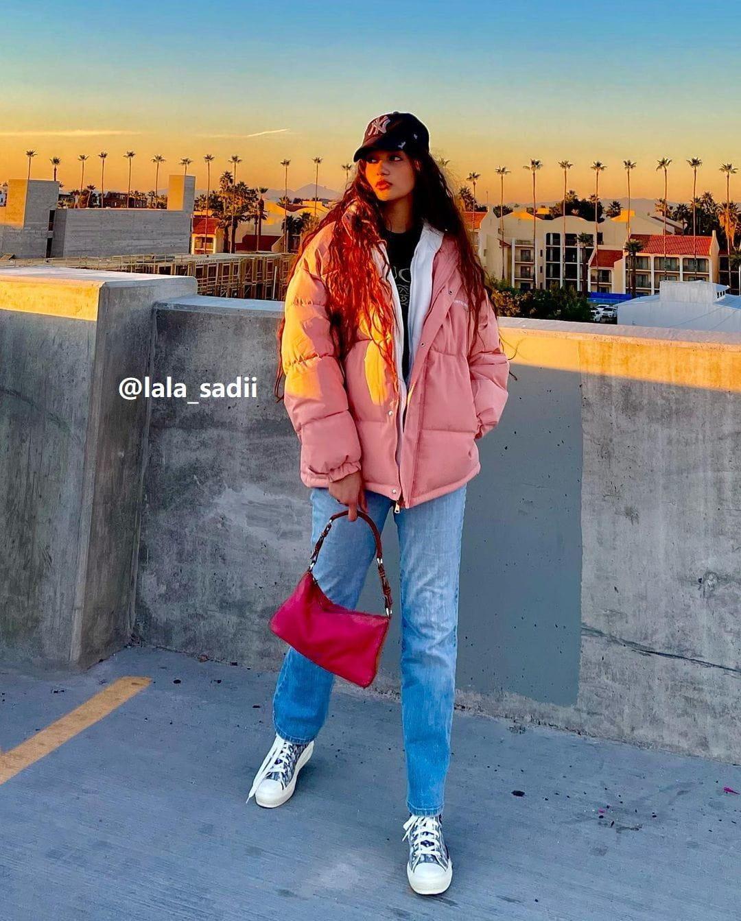 Model wearing a pink hooded winter coat by TALISHKO, styled with casual jeans and sneakers.