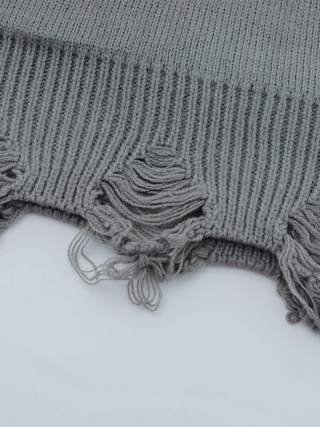 Detailed fabric and stitching of the gray TALISHKO sweater, highlighting its unique ripped design.