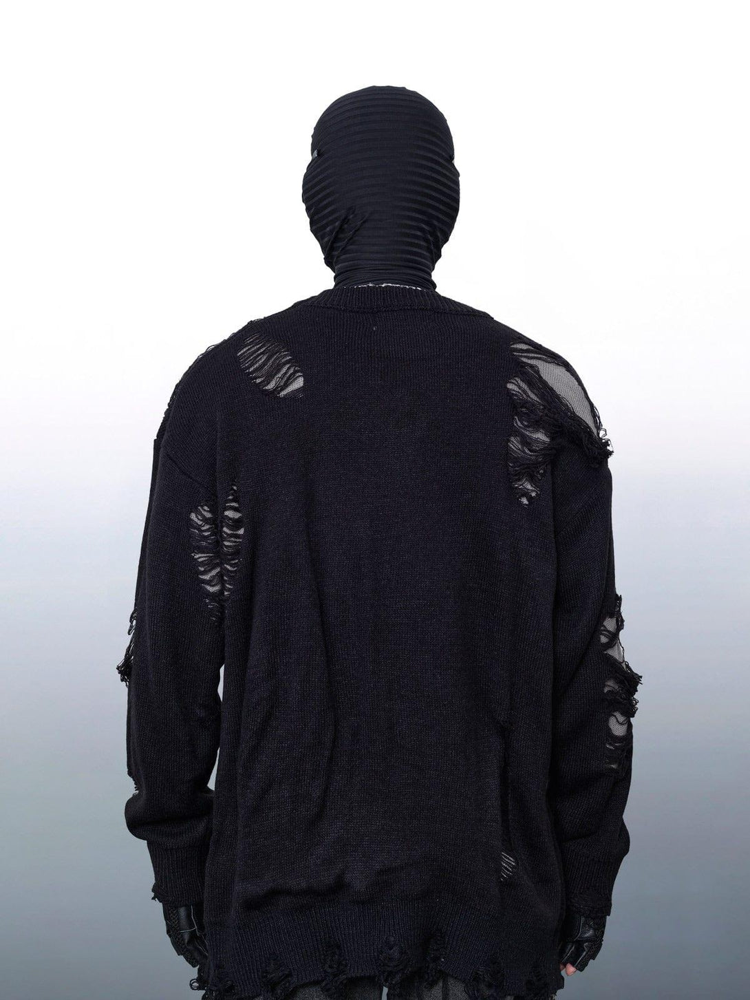 Back view of a black TALISHKO sweater with ripped details, showcasing an avant-garde style.