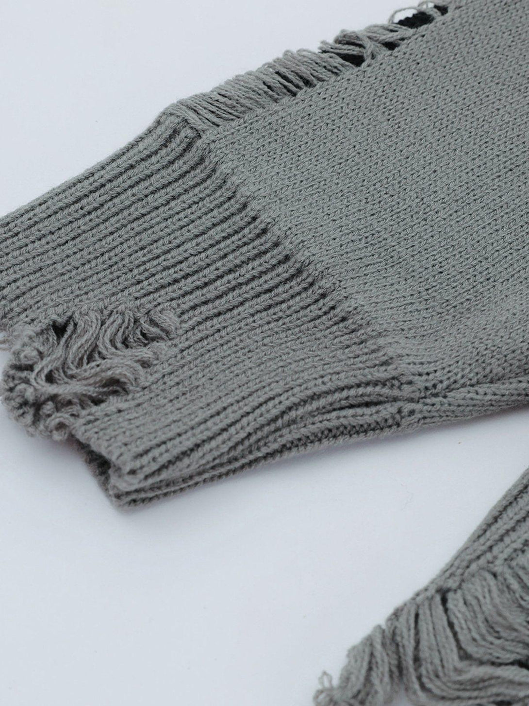 Intricate look at the gray TALISHKO sweater's fringe and knit texture, highlighting its unique style.