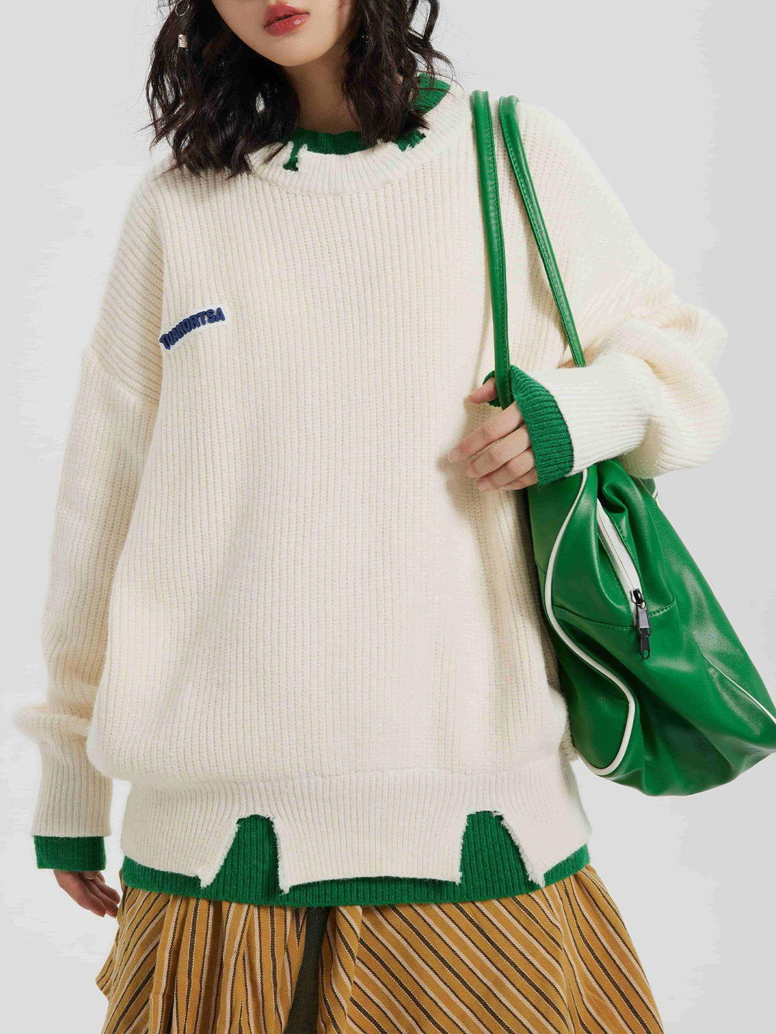 Model wearing TALISHKO's fake two sweater with green accents and a relaxed fit, paired with a green bag.