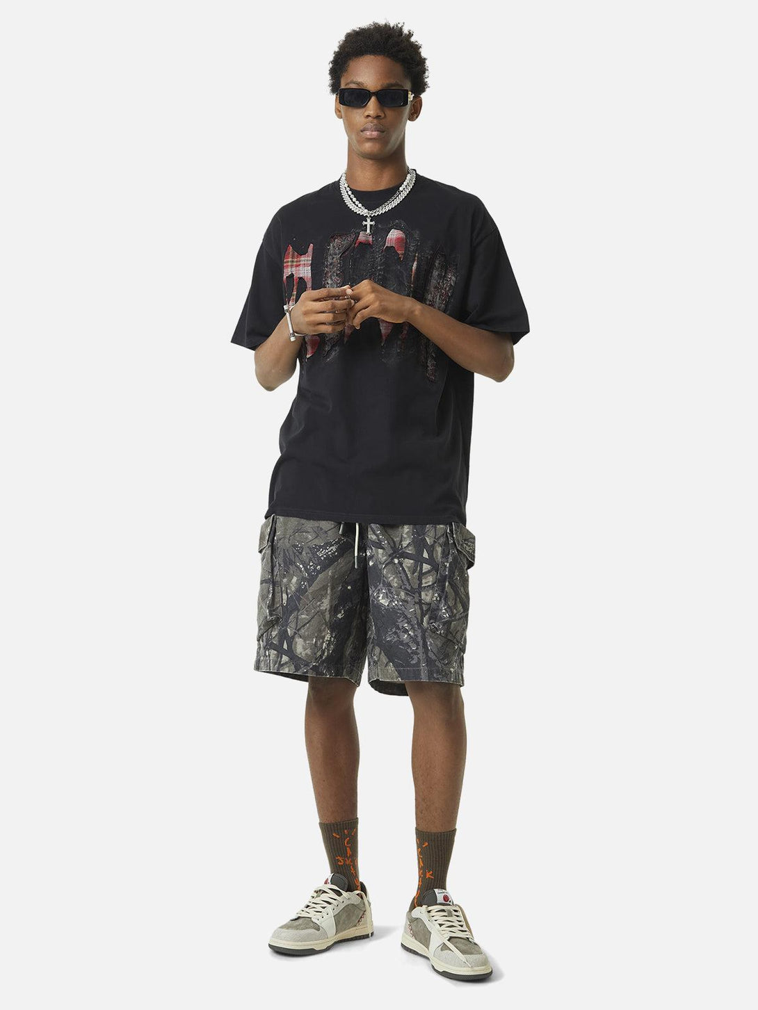 Model in TALISHKO graphic tee and camouflage shorts, embodying bold urban fashion.