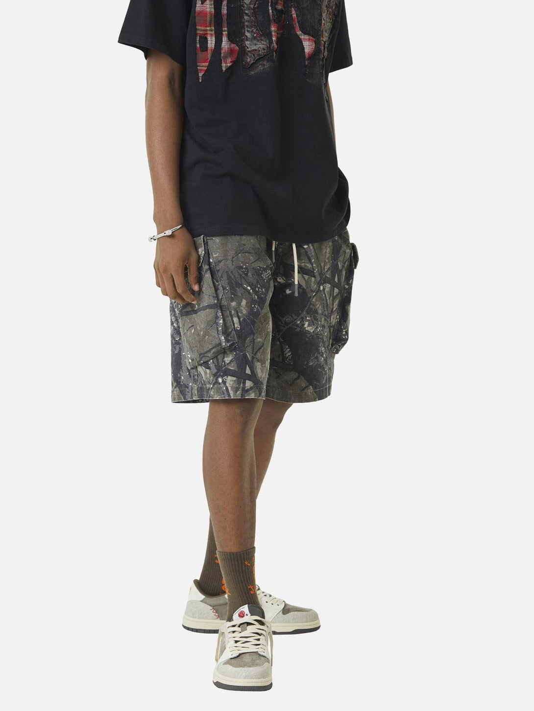 Model wearing TALISHKO camouflage shorts and graphic tee, embodying relaxed urban style.