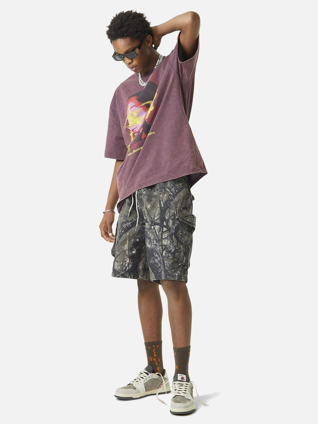 Model in TALISHKO camouflage shorts and graphic tee, highlighting a laid-back street style.