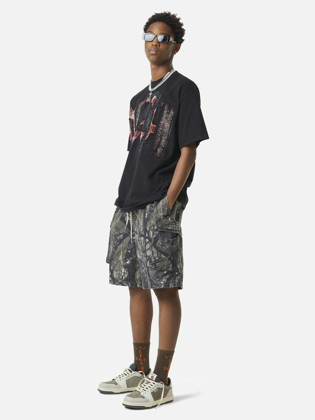 Model wearing TALISHKO's graphic tee and camouflage shorts, embodying a casual street vibe.
