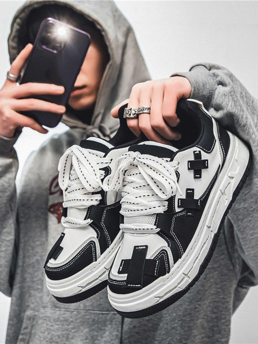 Fashion-forward thick-soled board shoes by TALISHKO, held by a model in casual streetwear.