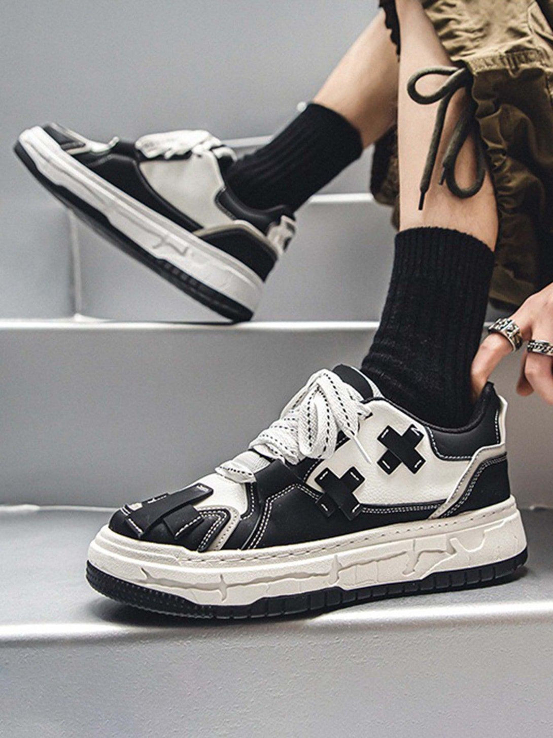 Stylish thick-soled board shoes by TALISHKO in black and white, worn with casual attire.