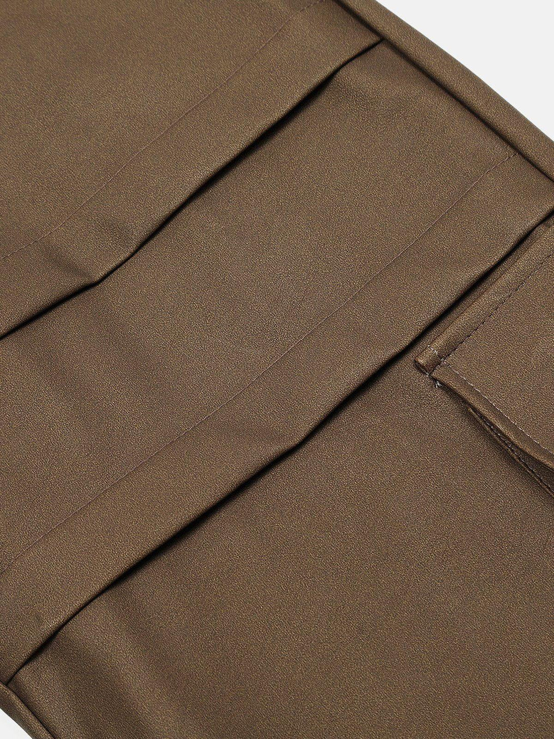 Detailed fabric and stitching of brown faux leather cargo pants by TALISHKO, emphasizing pocket design.