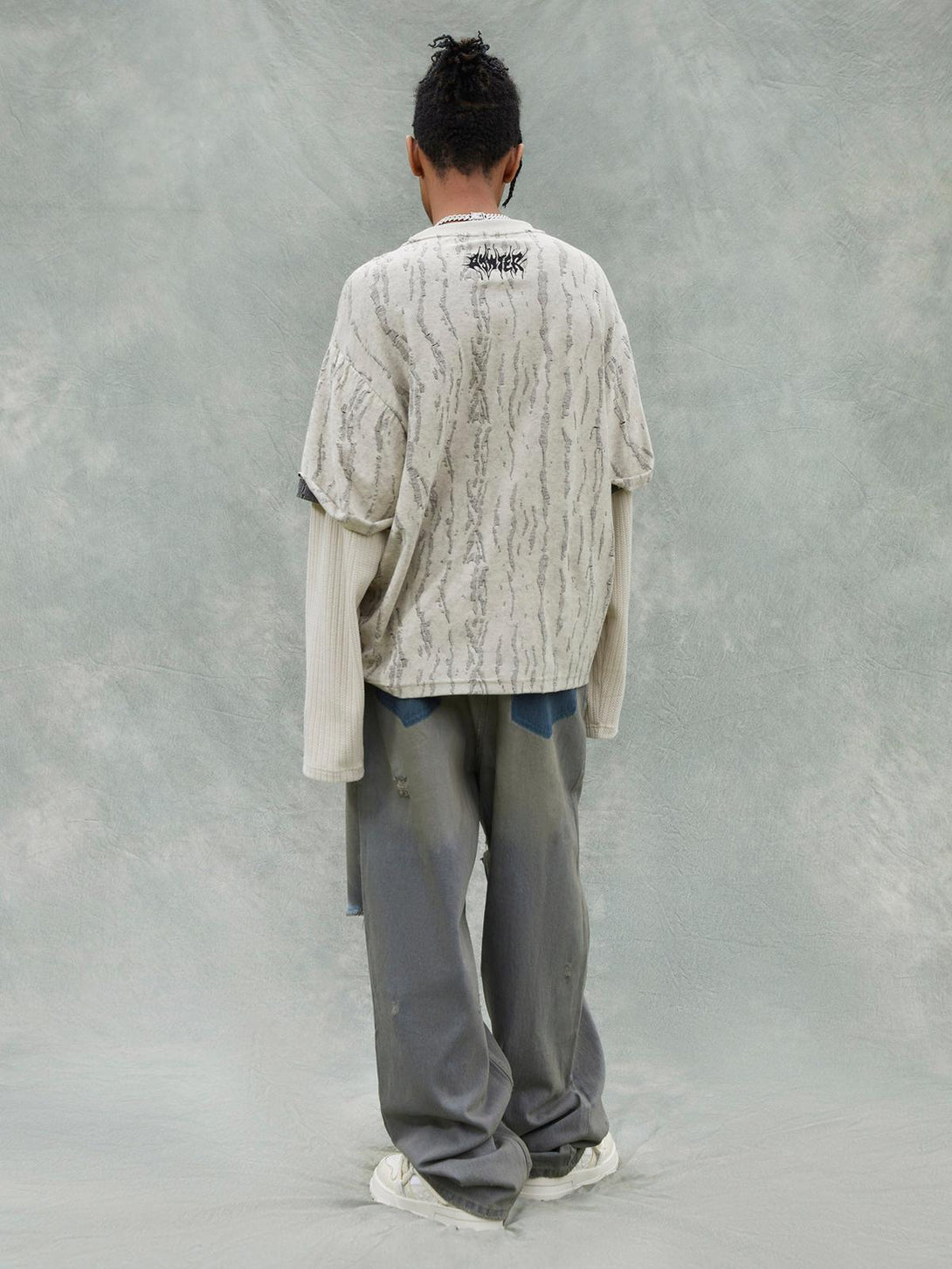 Back view of a model in TALISHKO's distressed faux two-piece T-shirt with layered sleeves.