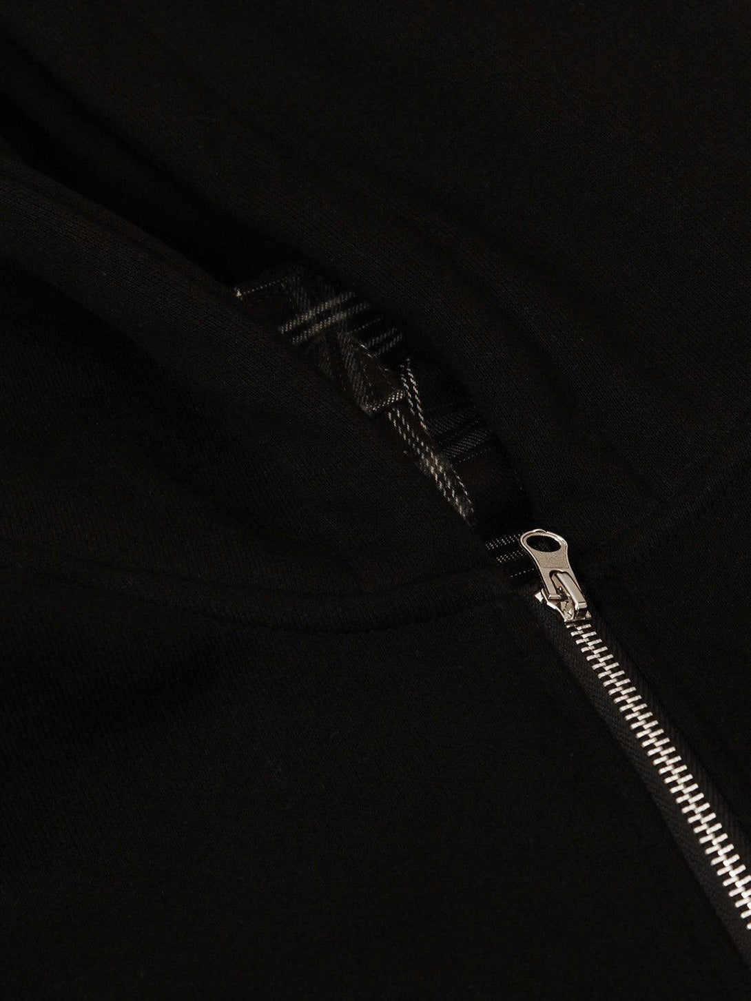 Focusing on the TALISHKO jacket's zipper, highlighting the sleek design and plaid detail.