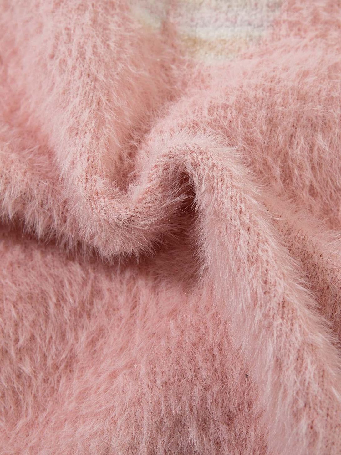Intricate look at the pink fuzzy texture of a sweater by TALISHKO, showcasing cozy elegance.