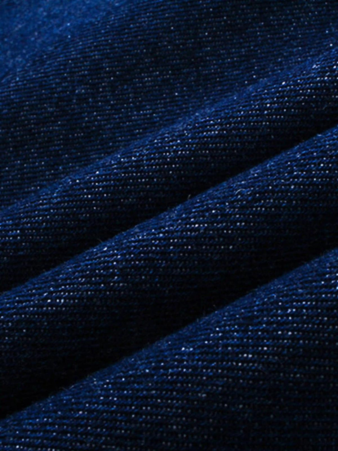 "Zoomed-in texture of TALISHKO's flame-scarred denim, highlighting intricate embroidery."