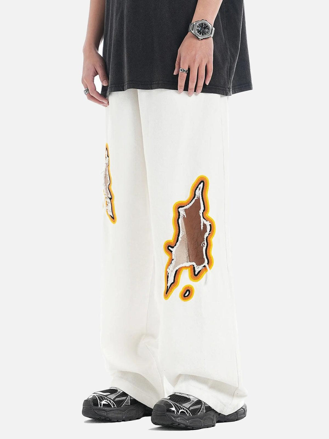 White flame-scarred embroidered jeans by TALISHKO, featuring bold patches and relaxed fit.