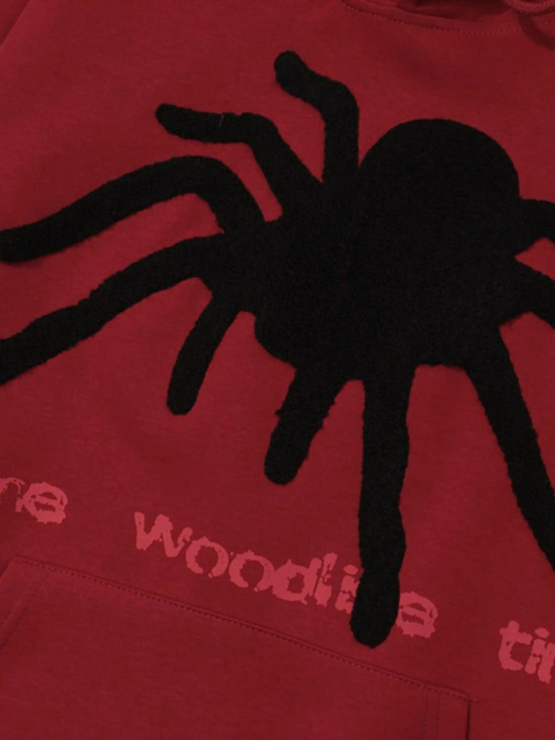 A close-up of the red TALISHKO hoodie featuring a bold black spider design and textured details.