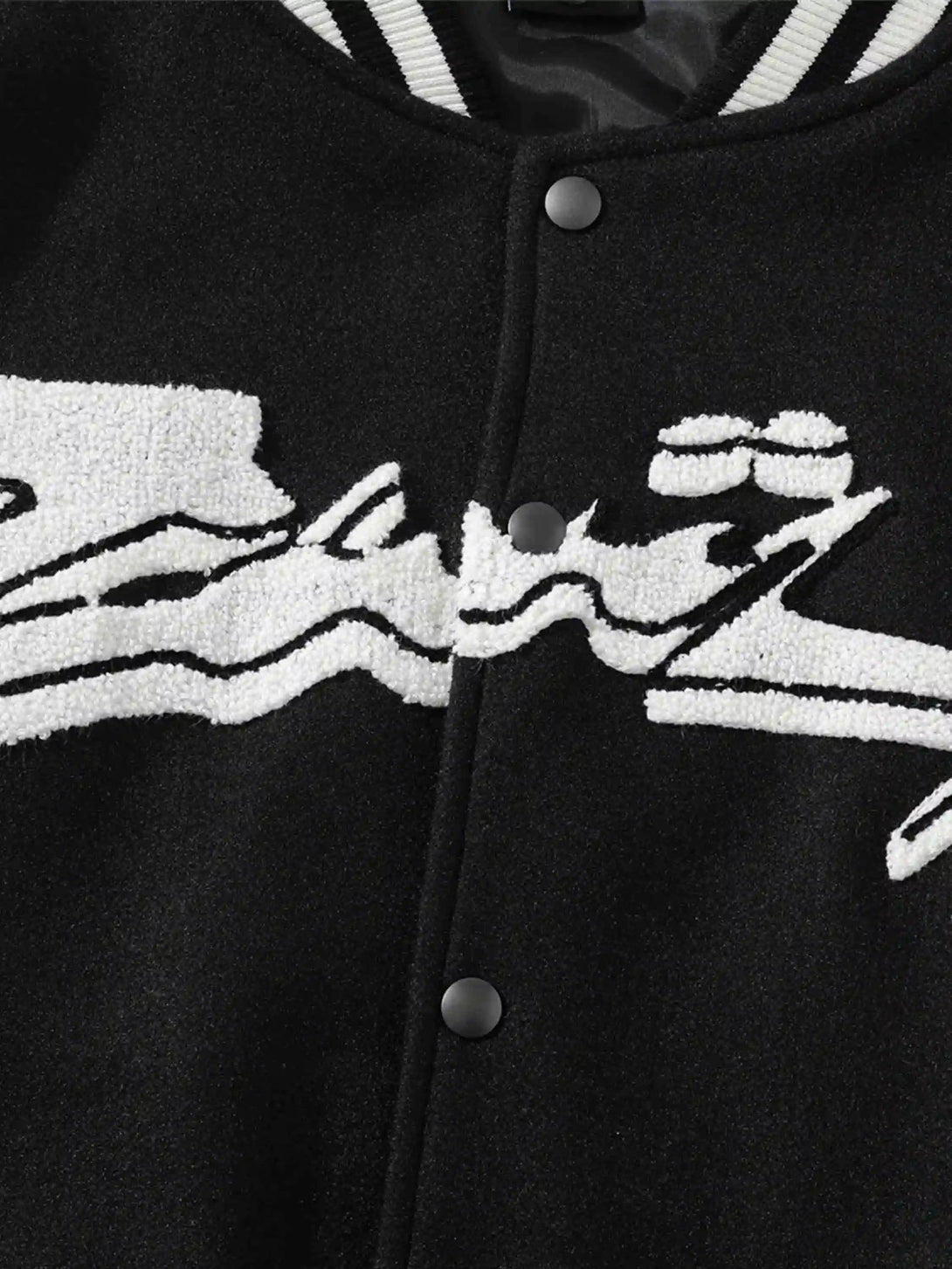 Intricate look at the embroidery detail on a black baseball jacket by TALISHKO.