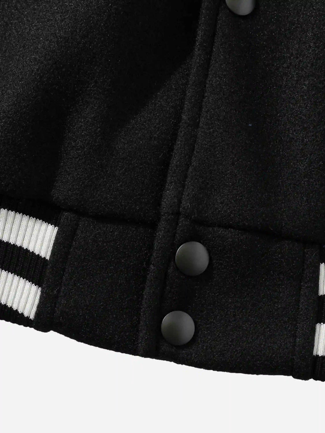 A close look at the buttons and striped hem of a TALISHKO baseball jacket in black.