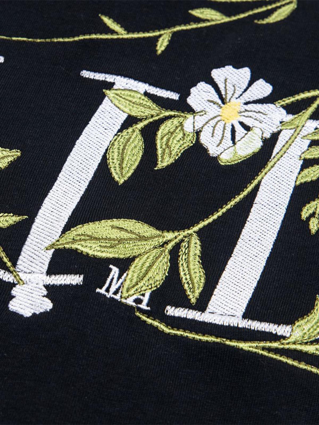 Intricate embroidery detail of a floral design on a black t-shirt by TALISHKO.