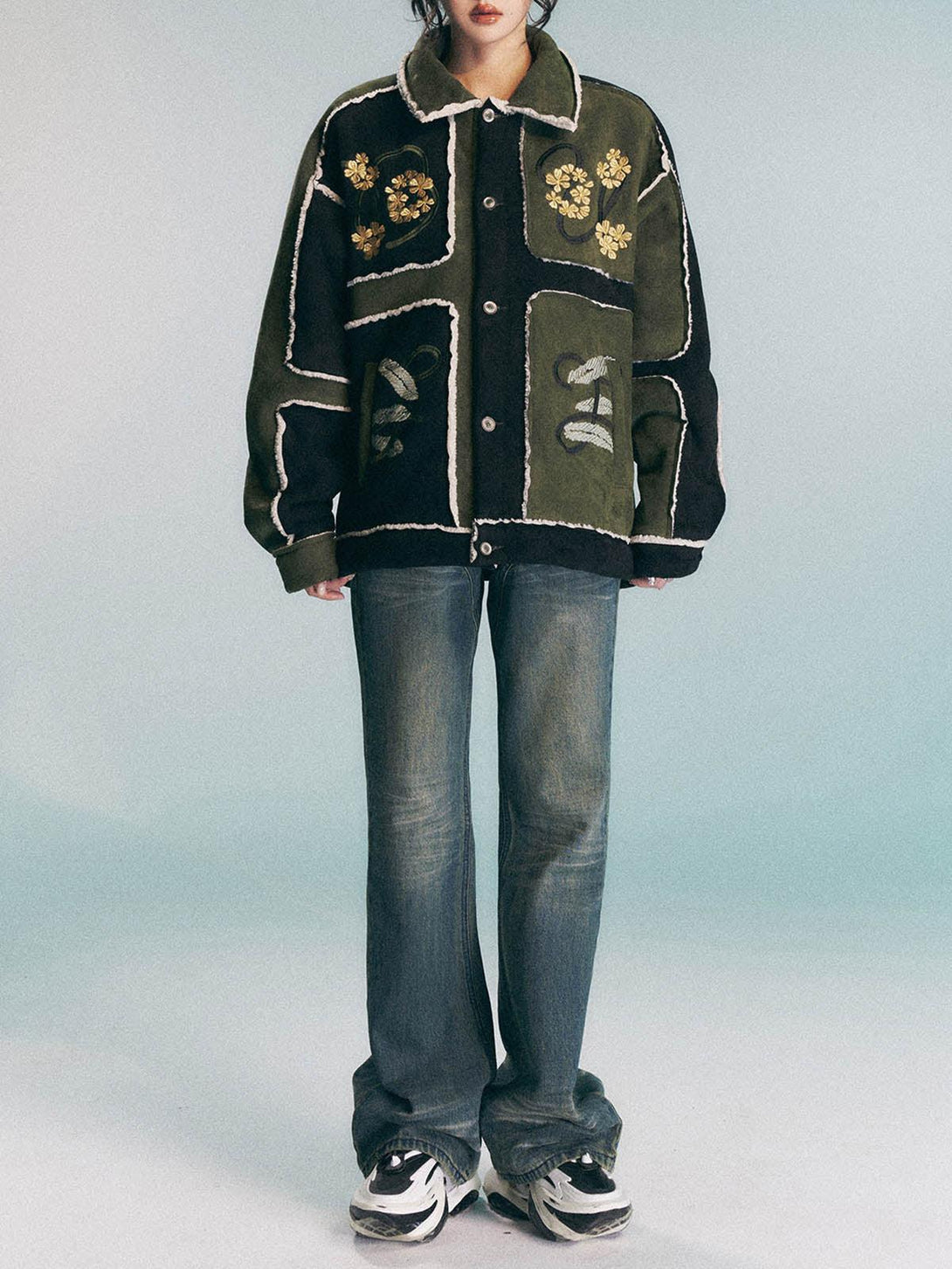 Model in TALISHKO's floral embroidered suede fleece jacket, paired with jeans and sneakers.