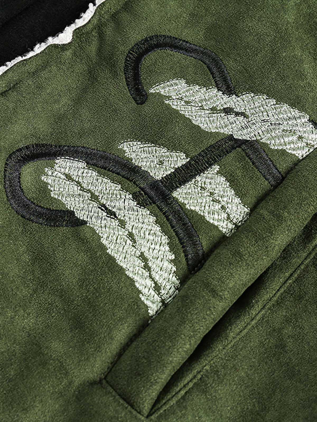 Intricate look at TALISHKO's floral embroidery on a green suede fleece jacket, highlighting texture.
