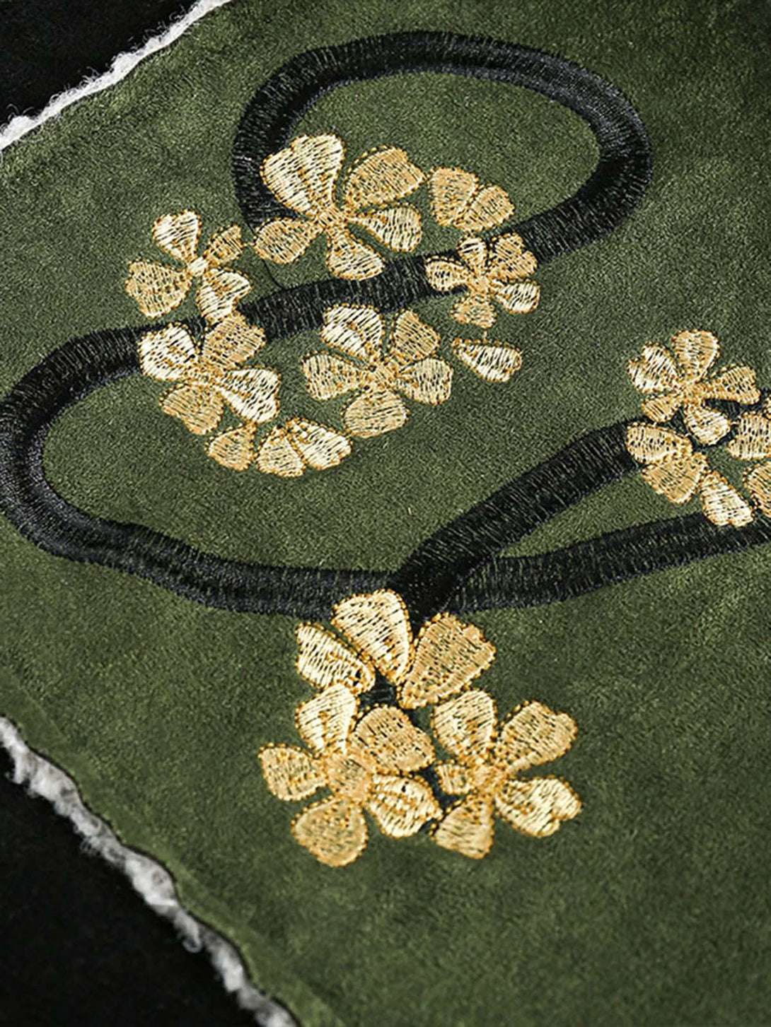 "Zoomed-in view of TALISHKO's floral embroidery on a green suede fleece jacket, showcasing detail."