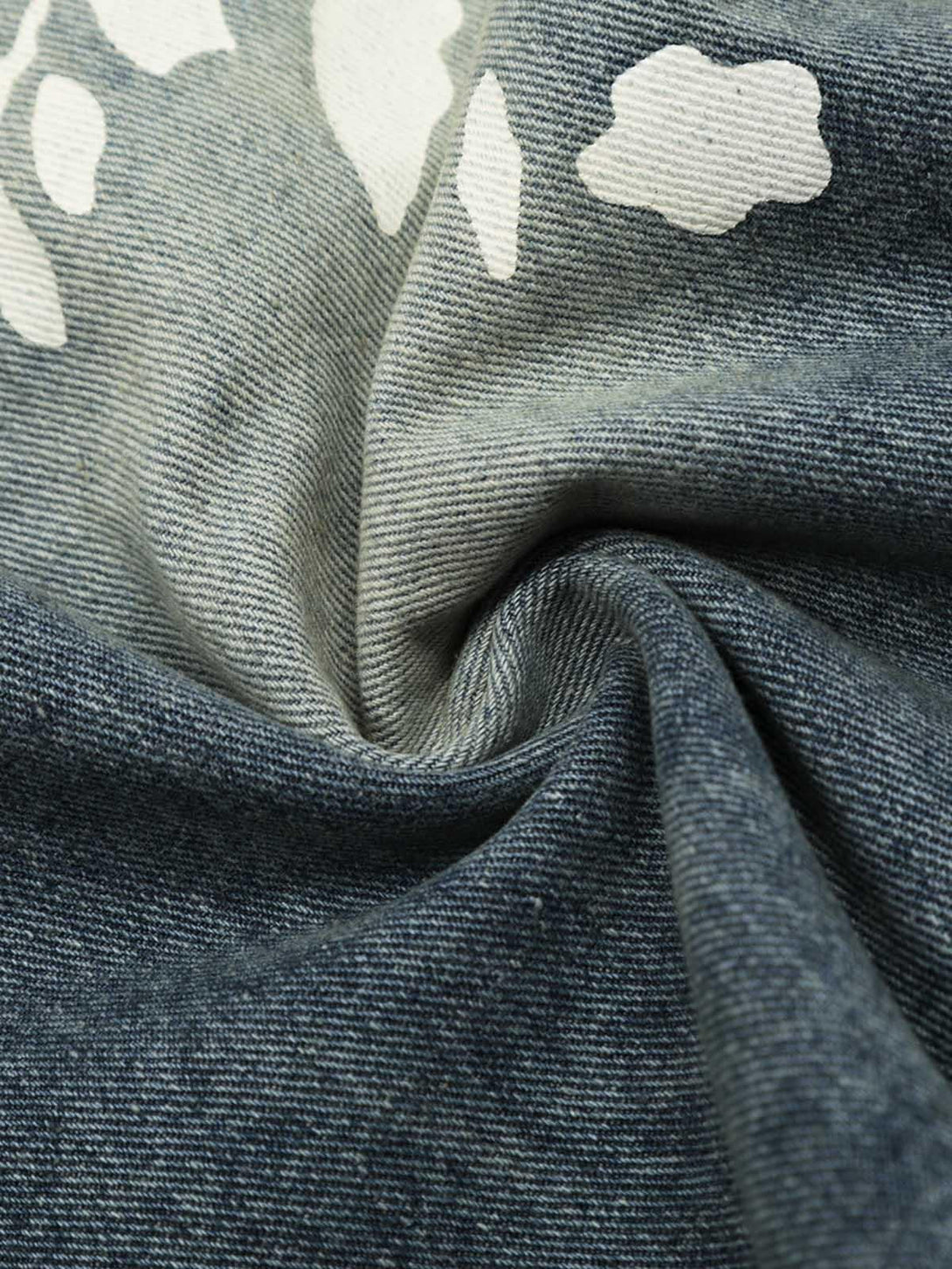 Zoomed-in texture of TALISHKO denim shorts, showcasing a unique floral pattern detail.
